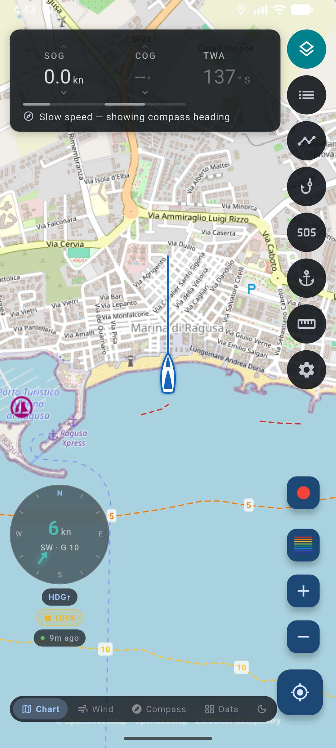 Chart helm off Marina di Ragusa: live SOG, COG, and TWA columns, heading-up wind dial, SOS above Anchor, sailboat marker with heading ray, Chart / Wind / Compass / Data.